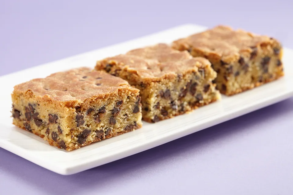 Three chocolate chip blondies on a white plate