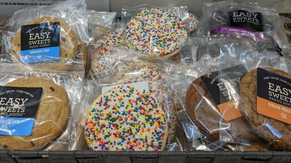 Individually wrapped Easy Sweets cookies and treats displayed at a café counter