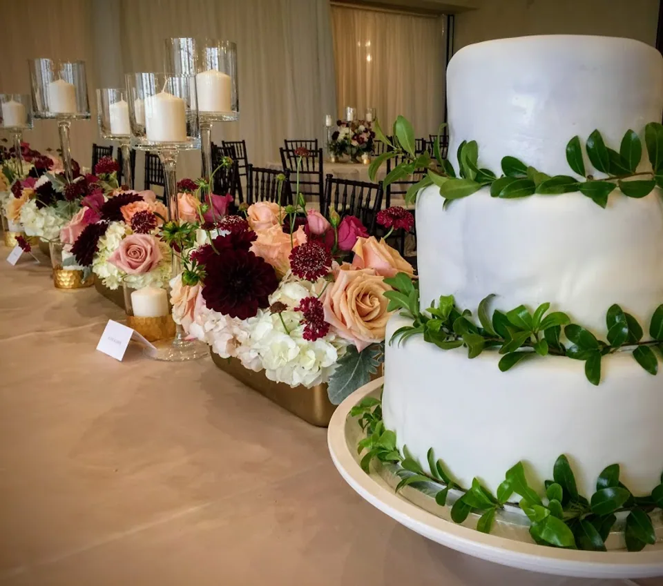 Sweet table with a white tiered cake, greenery and flowers
